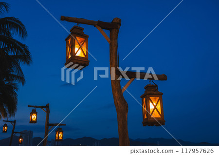 An old street lamp illuminating a dark street with palm trees An old street lamp illuminating a dark street with palm trees 117957626