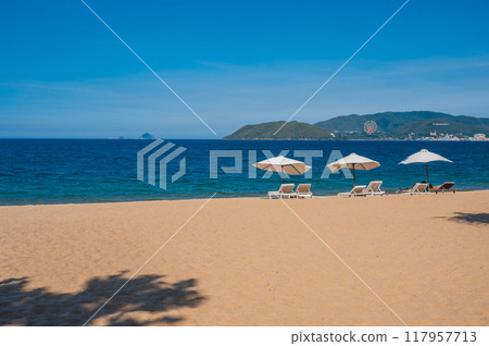 beach umbrellas with sun loungers without people on a sandy beach against the background of the sea beach umbrellas with sun loungers without people on a sandy beach against the background of the sea 117957713