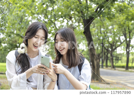 Happy teenage  girls having fun while using mobile phone in  school 117957890