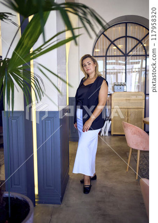 a middle-aged plus size woman in old money style clothes in a fancy restaurant a middle-aged plus size woman in old money style clothes in a fancy restaurant 117958320