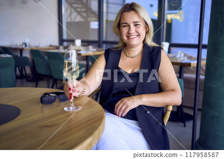 middle-aged plus size woman in old money style clothes drinking sparkling wine in a fancy restaurant middle-aged plus size woman in old money style clothes drinking sparkling wine in a fancy restaurant 117958587