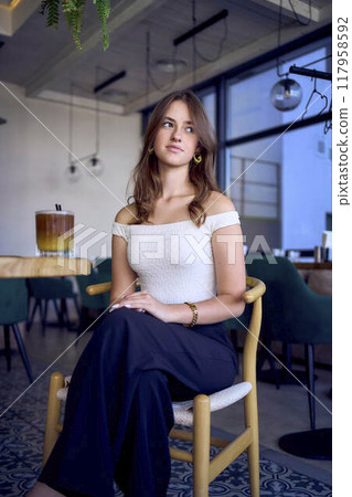 16-year-old teenage girl in old money style clothes drinks bumble coffee with an orange in a fancy restaurant 117958592