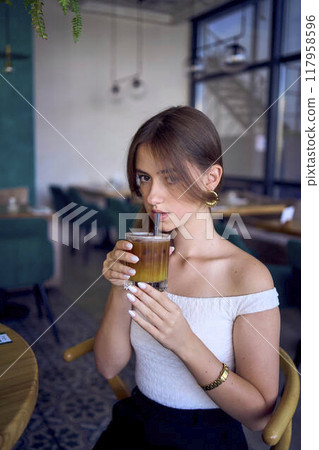 16-year-old teenage girl in old money style clothes drinks bumble coffee with an orange in a fancy restaurant 16-year-old teenage girl in old money style clothes drinks bumble coffee with an orange in a fancy restaurant 117958596