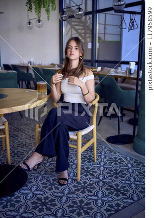 16-year-old teenage girl in old money style clothes drinks bumble coffee with an orange in a fancy restaurant 117958599