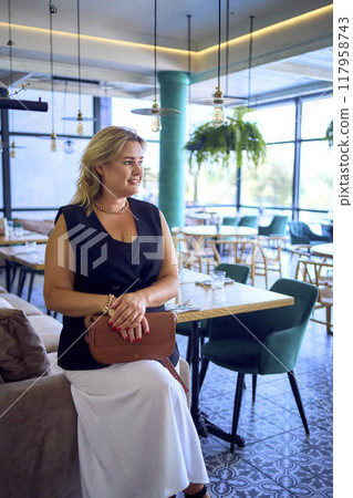 a  middle-aged plus size woman in old money style clothes in a fancy restaurant 117958743