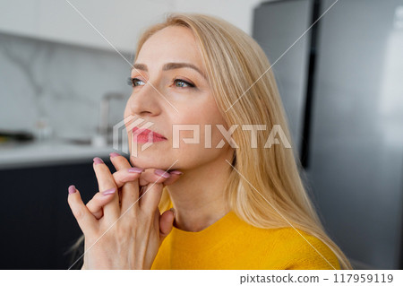 A blonde woman working from home, writing notes and using a laptop at a white desk A blonde woman working from home, writing notes and using a laptop at a white desk 117959119