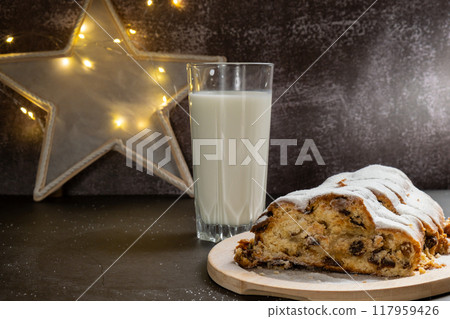 Traditional German Christmas stollen cake with glass of milk for SANTA in background of handmade festive decor. Winter holiday treats. Vegan baking recipe 117959426