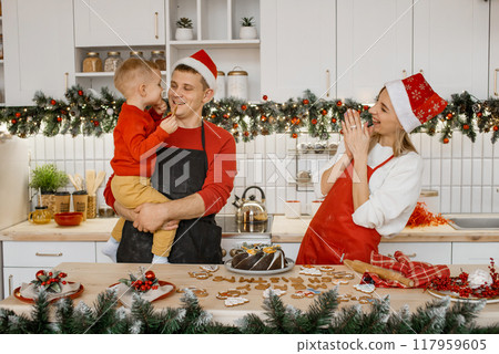 Happy family in santa hats laughing and having fun in the kitchen after finish decorating gingerbread cookies 117959605