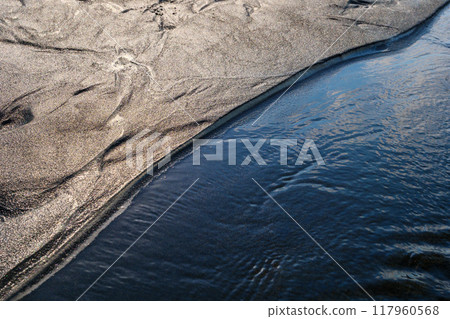 Rippling water meets shimmering sand in a tranquil nature setting 117960568