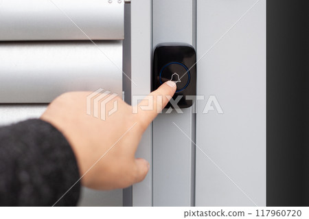 Close-Up of Hand Pressing a Wireless Doorbell 117960720