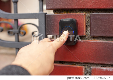 Hand Pressing Doorbell on Red Brick Wall Hand Pressing Doorbell on Red Brick Wall 117960726