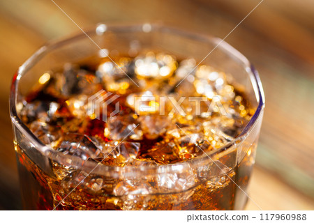 Cola and whiskey in a glass with ice cubes close-up Cola and whiskey in a glass with ice cubes close-up 117960988