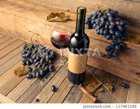 Bottle of red wine and blue grapes on a old wooden table. Bottle of red wine and blue grapes on a old wooden table. 117961206