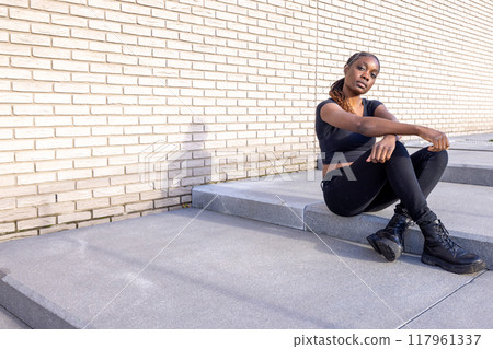 A Stylish Woman Posing Confidently on Concrete Steps while Surrounded by an Urban Background 117961337