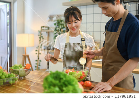Happy young couple preparing a fresh and healthy salad together in modern kitchen 117961951