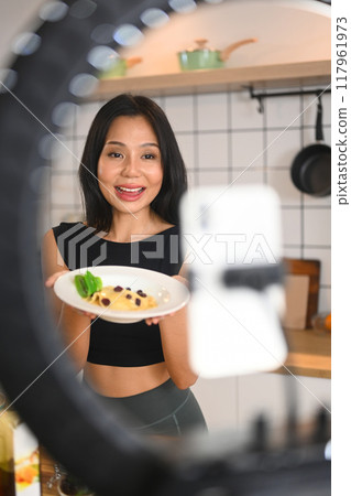Uoung woman using smartphone on tripod for recording video healthy vegetable salad cooking tutorial Uoung woman using smartphone on tripod for recording video healthy vegetable salad cooking tutorial 117961973