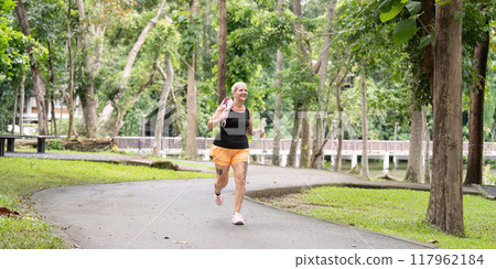 Senior woman jogging through scenic park trail Senior woman jogging through scenic park trail 117962184