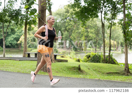 Senior woman walking briskly in scenic park setting 117962186