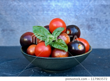 Black and red tomatoes in a bowl on the stone table. Black and red tomatoes in a bowl on the stone table. 117963572