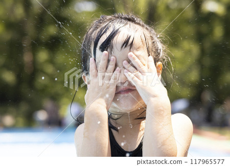 Girl enjoying splashing around in the pool Girl enjoying splashing around in the pool 117965577