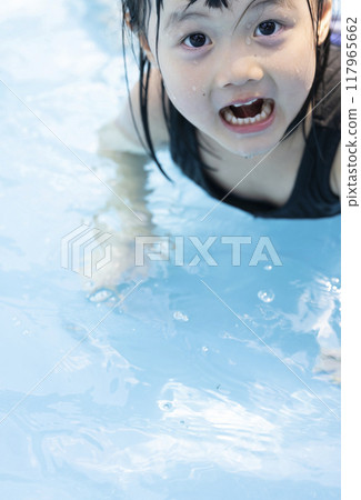 Cute little girl having fun splashing around in the pool 117965662