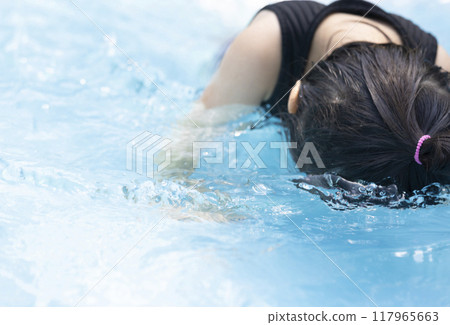 Cute little girl having fun splashing around in the pool 117965663