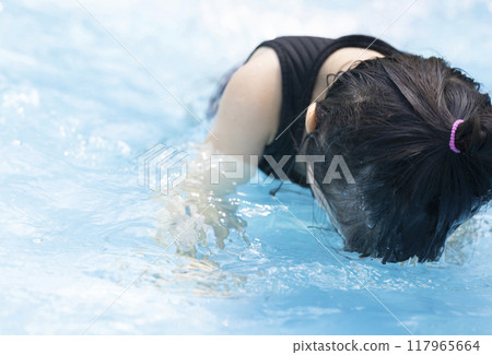 Cute little girl having fun splashing around in the pool 117965664