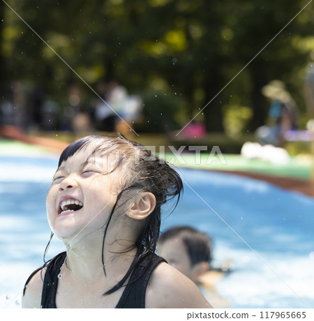 Cute little girl having fun splashing around in the pool 117965665