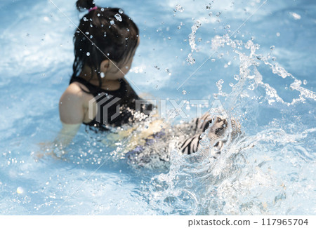 Girl enjoying splashing around in the pool Girl enjoying splashing around in the pool 117965704