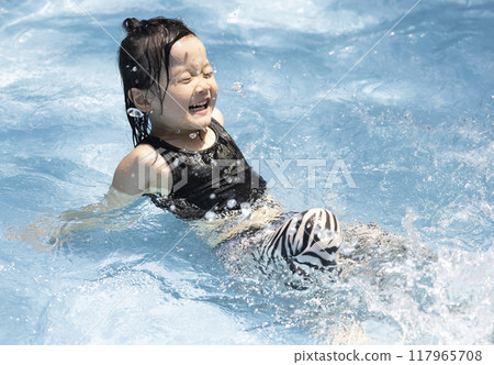 Girl enjoying splashing around in the pool 117965708