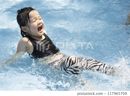 Girl enjoying splashing around in the pool Girl enjoying splashing around in the pool 117965709