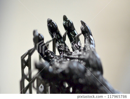Model of hand printed on a 3D printer from black rubber, close-up. Part of an object created on a 3D printer from hardened rubber under the influence of ultraviolet light. SLA 3D printing technology. 117965786