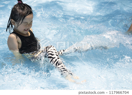 Girl enjoying splashing around in the pool 117966704