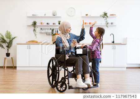 Muslim mother in wheelchair with daughter using smartphone 117967543