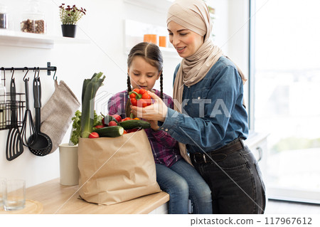 Mother and daughter unpacking groceries in kitchen together Mother and daughter unpacking groceries in kitchen together 117967612