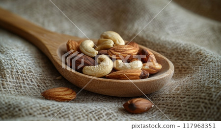 A wooden spoon holds an assortment of assorted nuts on a textured fabric background 117968351