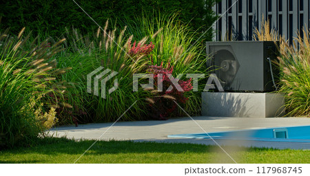 Heat pump unit near a backyard pool, surrounded by lush plants and vibrant flowers, showcasing modern sustainable living. 117968745
