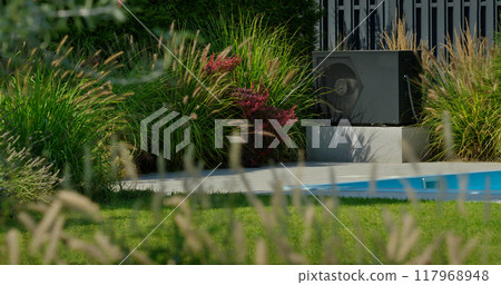 Outdoor heat pump unit next to a backyard pool, surrounded by lush, blooming vegetation. 117968948