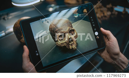 Archaeologist takes photo of prehistoric extinct human skull using tablet computer 117969273