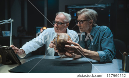 Two archaeologists talk and study skull of ancient extinct human, use tablet computer 117969332