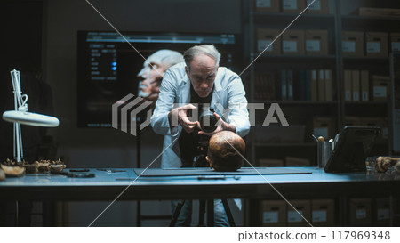 Senior archaeologist takes photo of prehistoric human skull with professional camera Senior archaeologist takes photo of prehistoric human skull with professional camera 117969348