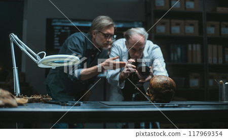 Two archaeologists photograph fossil skull with professional camera 117969354