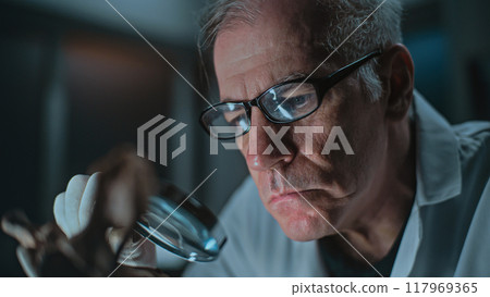 Senior archaeologist does historical bone examination using magnifying glass Senior archaeologist does historical bone examination using magnifying glass 117969365