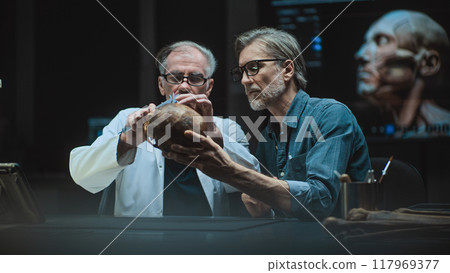 Two archaeologists conduct scientific research on prehistoric human skull 117969377