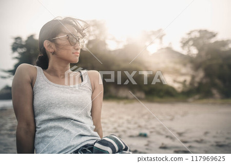 A young woman wearing sunglasses at the beach 117969625