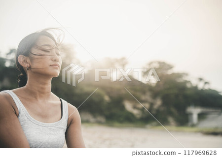 黃昏時分，海邊戴著墨鏡的年輕女子 117969628