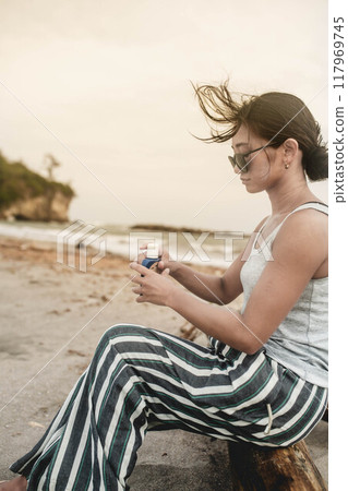 Young Japanese woman doing skin care at the beach Young Japanese woman doing skin care at the beach 117969745