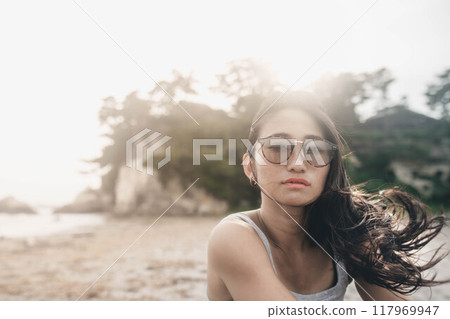 Young Japanese woman wearing sunglasses on a windy sandy beach Young Japanese woman wearing sunglasses on a windy sandy beach 117969947