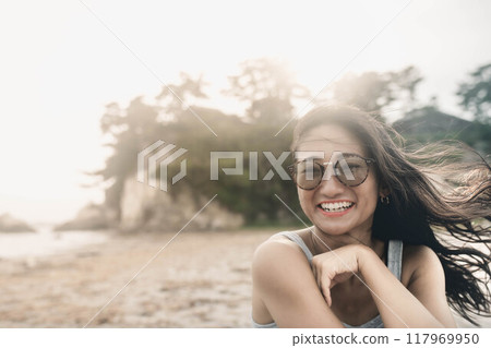 Young Japanese woman wearing sunglasses on a windy sandy beach Young Japanese woman wearing sunglasses on a windy sandy beach 117969950