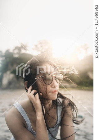 Young Japanese woman wearing sunglasses on a windy sandy beach Young Japanese woman wearing sunglasses on a windy sandy beach 117969962